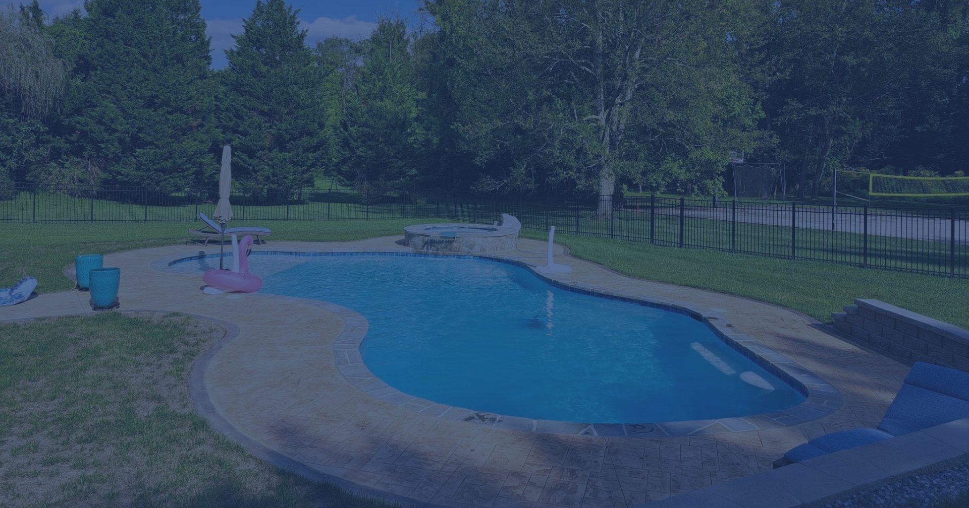 Aerial view of a suburban brick house with a fenced backyard and swimming pool.